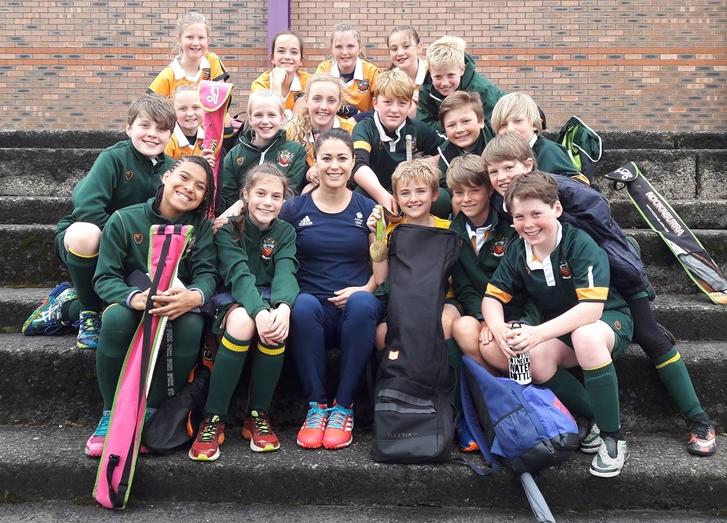 Olympic gold medalist and hockey player Sam Quek sits on the steps at the university of manchester with boy and girl junior students from cheadle hulme school's u11s hockey teams