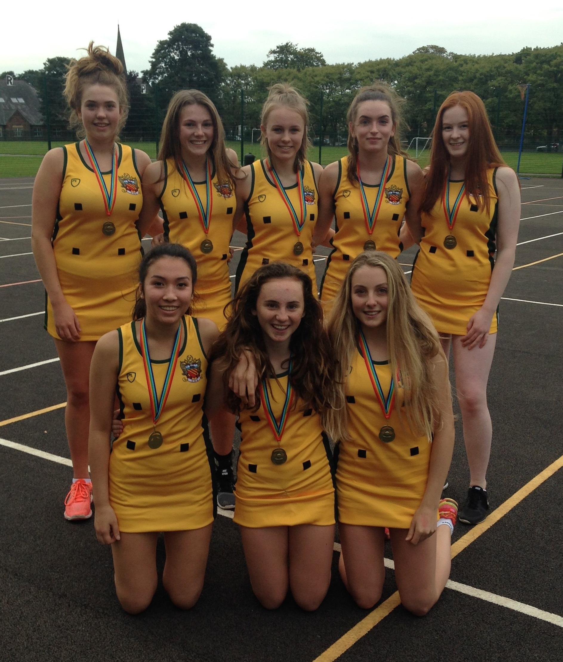 cheadle hulme school's under 16s netball team stand on the courts wearing medals as winners of all 7 games of their matches at the stockport schools netball tournament